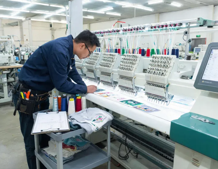 Technician checking needle bars on a Tajima embroidery machine